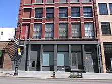 A view of a storefront with frosted windows, grey surround, and red brick building above.