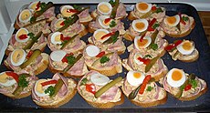 Obložené chlebíčky prepared with a spread, ham, hard-boiled egg, red bell pepper, pickle and parsley