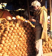 Many stacked coconuts, with man