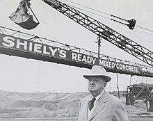 Joe Shiely stands in gravel pit with sand loader in the background
