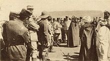 Французские и марокканские мужчины толпятся вокруг центральных фигур Хасана и Поеймирау, обсуждая