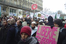 Muslims march in Paris on 11 February 2006 against the publication of caricatures of Muhammad. A sign with "Charlie Hebdo" circled and crossed-out is held aloft in the picture's upper middle. Paris 2006-02-11 anti-caricature protest bannieres dsc07473.jpg