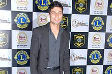 Hooda in a grey suit posing for the camera.