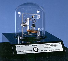 1947年11月由貝爾實驗室研製出的第一個電晶體（複製品），透明鐘罩將塑料和電線等組件與外界隔離，上面的牌匾紀念電晶體誕生50週年