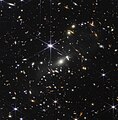 Webbovo prvé hlboké pole – kopa galaxií SMACS 0723 v súhvezdí Lietajúca ryba. Hmota klastra vzdialeného 4 miliardy ly funguje ako gravitačná šošovka, zobrazujúca ešte vzdialenejšie galaxie.