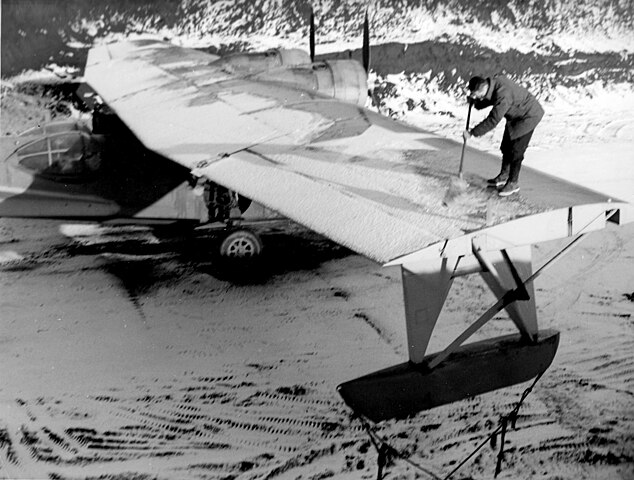 A U.S. Navy ground crew member removes the snow from a Consolidated PBY-5A Catalina at an Alaskan base, circa in 1943.