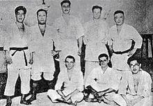 Huit judokas, cinq debout, et trois assis au sol, posant pour une photo.