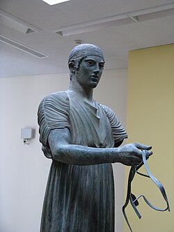 Delfoin ajomies, Python kisojen voittajaa esittävä pronssiveistos. Delfoin arkeologinen museo.