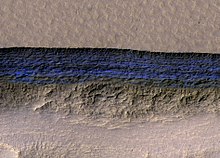 A cross-section of Mars underground ice is exposed at the steep slope that appears bright blue in this enhanced-color view from the MRO. The scene is about 500 meters wide. The scarp drops about 128 meters from the level ground in the upper third of the image Mars exposed subsurface ice.jpg