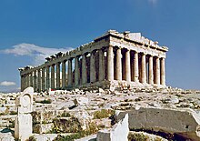 The Parthenon is a rectangular building of white marble with eight columns supporting a pediment at the front, and a long line of columns visible at the side