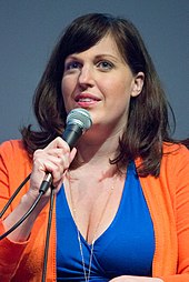 A photograph of Tolman speaking with a microphone in 2015