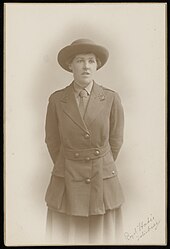 Letitia Fairfield trägt Armeeuniform: Hut mit breiter Krempe, Krawatte, und Kurzmantel über einem Rock. Abzeichen und Knöpfe weisen sie als Angehörige des medizinischen Dienst aus.