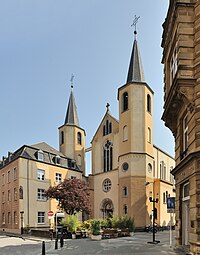 D'Paterekierch an der Stad. Lénks d'Klouschtergebai mat der Statu vum hl. Alphonsus um Eck.