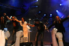 Cinq membres d'un groupe se tenant par la main à la fin d'un de leurs concerts.