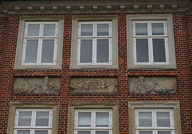 The three central reliefs on the facade, depicting a barge flanked by Neptune and Mercury.