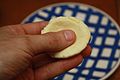 A small piece of dough being flattened in someone's hand