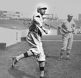 A black-and-white picture of a man wearing an old-style baseball uniform running on a field