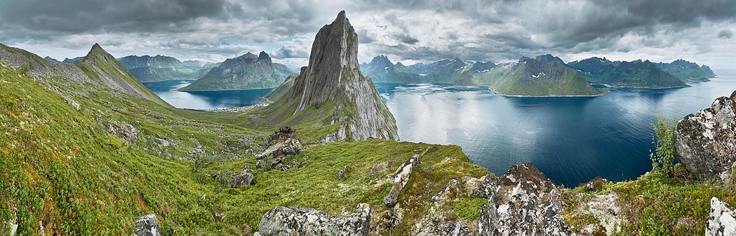 Panorama zachycené z horského hřbetu mezi vrcholy Segla a Hesten na ostrově Senja, ležícím v norském kraji Troms. Od centrálně postaveného vrcholu Segla (640 m n. m.) se nalevo vine fjord Øyfjorden a napravo pak fjord Mefjorden.