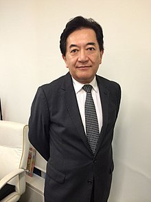 Author Yasuo Tanaka in 2014, wearing a suit, standing with hands behind back