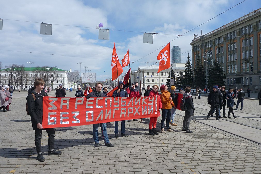 Последняя коробка пятой колонны. За ней видны мужчина (Юлиан Титов) и женщина. Оба с плакатами. 13:52