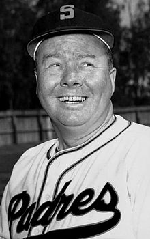 A man in a light baseball uniform and dark cap