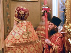 A deacon holds a red paschal deacon's candle at paschal matins (The Trinity Lavra, in Sergiyev Posad, Russia). PaschalMatins.DeaconHoldingRedCandle.jpeg