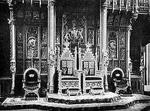 The royal thrones, c. 1902. The Sovereign's throne (on left) is raised slightly higher than the consort's. Thrones in the House of Lords c1902.jpg