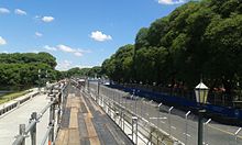 Photographie d'une rue de Buenos Aires, entourée d'arbres, sous un ciel bleu.