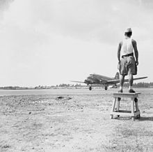 A Japanese prisoner of war watching a British Royal Air Force Dakota transport landing at Bandoeng, Java, during May 1946. Japanese POW in Java during 1946.jpg