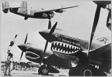 A Consolidated Liberator I flying over Curtiss P-40 Warhawks of the U.S. Army Air Forces in 1943 Landing wheels recede as this U.S. Army Air Forces Liberator bomber crosses the shark-nosed bows of U.S. P-40 fighter... - NARA - 535780.tif