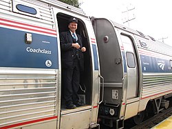 Кондуктор Amtrak стоит в дверях вагонов Amfleet с закрытым люком