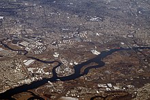 Aerial view of the Arthur Kill, a tidal strait that separates New Jersey (above) from Staten Island (below). Outerbridge Crossing connects the two, at the south end of Staten Island. Crossing its north end is the Goethals Bridge. The water body perpendicular to the Arthur Kill in New Jersey is the Rahway River. which divides Carteret on the south (left) and Linden on the north. The island in Arthur Kill is Prall's Island.