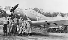 Photographie noir et blanc. Six hommes devant l'avion.