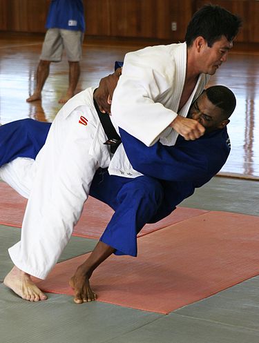 Execution of a judo throw (ōuchi-gari). The player in blue is being thrown.