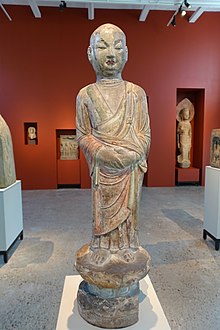 Statue of East Asian monk holding hands in front of belly