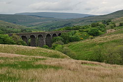 A stone viaduct at the head of a valley with steep sided hills all around