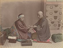 A doctor checks a patient's pulse in Meiji-era Japan. Doctor (Kusakabe Kimbei).jpg