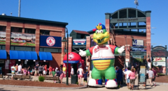 The brick fascade of a ballpark with an inflatable greem alligator mastcot infront