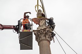 Sochař Petr Váňa umisťuje sochu na vrchol sloupu