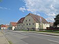 Wohnhaus mit seitlichem Anbau, Scheune, Einfahrtspfeiler und Hofmauer eines großen Hofes