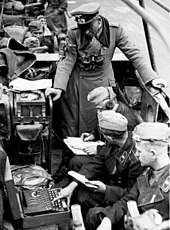 Heinz Guderian in the Battle of France, with an Enigma machine. Note one soldier is keying in text while another writes down the results. Bundesarchiv Bild 101I-769-0229-10A, Frankreich, Guderian, "Enigma" cropped.jpg