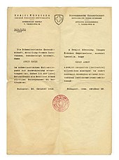 Photographie d'une lettre au papier jauni, portant un entête (préimprimé) et un corps de texte (tapé à la machine à écrire) en allemand et en hongrois, doté d'un tampon rouge au centre.