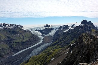 Blick von den Kristínartindar-Gipfeln auf den Morsárfoss in den Felsen in der Bildmitte; auf den Felsen liegt die Eiskappe des Vatnajökull, unterhalb von ihnen beginnt der Morsárjökull.