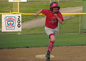 Softball player rounding second base after a hit.