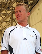 A man with blond hair wearing a white top