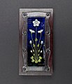 rectangular plaque with white flowers on a blue background, inset in silver