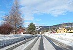 Foto einer Straße in einer verschneiten Ortschaft mit mehreren Wohnhäusern