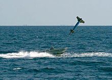 A GBU-10 Paveway II, an American laser-guided bomb, based on the Mk 84 general-purpose bomb, but with laser seeker and wings for guidance. Introduced into service c. 1976. GBU-10 shortly before it impacts a small boat during a training exercise.jpg