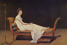 woman seated on a chaise looking over her shoulder at the viewer