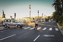 The white truck, a Renault Midlum, in the distance
on the Promenade des Anglais on the morning after the attack Lieu de l'attentat du 14 juillet 2016 a Nice cropped.jpg